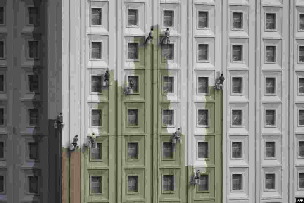 Chinese workers paint the side of a building in Shenyang, Liaoning province.