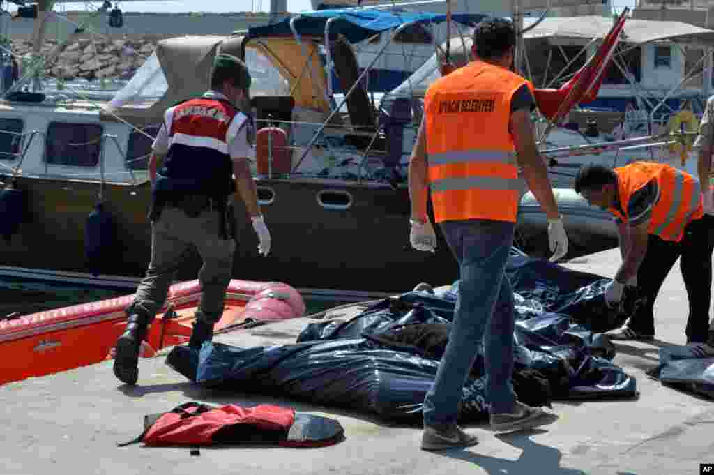 A Turkish paramilitary officer and local workers collect the bodies of migrants after their boat collided with a ferry off the Turkish coast near Ayvacik, Canakkale. Twenty six migrants were fear missing and search-and-rescue operations were ongoing, an official of Turkey&#39;s coast guard agency said.