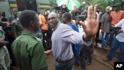 FILE - Evans Mawarire waves goodbye as he is taken into a prison truck at the magistrates courts in Harare.
