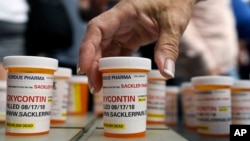 FILE - Family and friends who have lost loved ones to OxyContin and opioid overdoses leave pill bottles in protest outside the headquarters of Purdue Pharma, which is owned by the Sackler family, in Stamford, Conn., Aug. 17, 2018. 