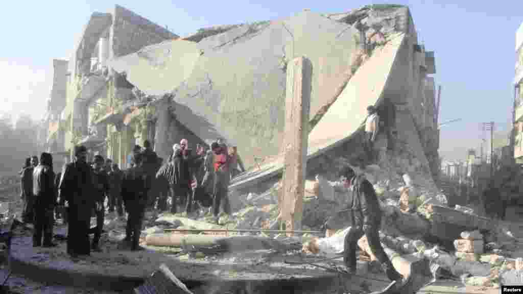 People inspect a site damaged by what activists said was an air raid by forces loyal to Syrian President Bashar Al-Assad in the al-Marja district of Aleppo, Dec. 23, 2013.&nbsp;