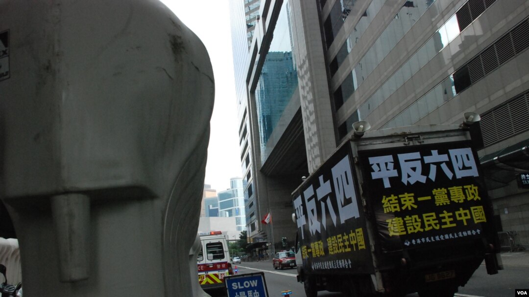 掛上平反六四等標語的香港支聯會「六四號」示威車，駛經香港警方佈置的水馬陣