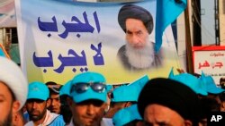 FILE - In this May 4, 2018 photo, followers of Shi'ite cleric Muqtada al-Sadr hold a poster of Shi'ite spiritual leader Grand Ayatollah Ali al-Sistani, during a parliamentary campaign rally in Baghdad.