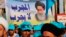 FILE - In this May 4, 2018 photo, followers of Shi'ite cleric Muqtada al-Sadr hold a poster of Shi'ite spiritual leader Grand Ayatollah Ali al-Sistani, during a parliamentary campaign rally in Baghdad.