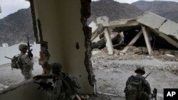 In this Tuesday, Nov. 3, 2009 photo, U.S. soldiers from the 2nd Battalion, 12th Infantry Regiment, 4th Brigade Combat Team, 4th Infantry Division wait inside a destroyed health clinic in the village of Qatar Kala in the Pech Valley of Afghanistan.