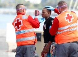 Red Cross members take the temperature of a migrant before disembarking from a Spanish coast guard vessel in the port of Arguineguin on the island of Gran Canaria, Spain, May 17, 2020.