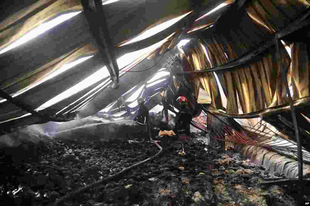 A Bangladeshi firefighter douses a fire that killed almost a dozen people at a garment factory in Gazipur outside Dhaka, Bangladesh.