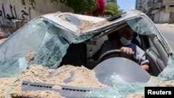 A Palestinian man drives his car, which was damaged in an Israeli airstrike, as he heads to a garage, in Gaza City.