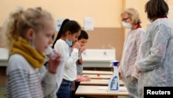 FILE - School children attend a COVID-19 saliva test in a primary school in Nice, as part of the coronavirus disease (COVID-19) testing campaign in France, March 8, 2021. 