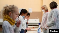 FILE - School children attend a COVID-19 saliva test in a primary school in Nice, as part of the coronavirus disease (COVID-19) testing campaign in France, March 8, 2021. 