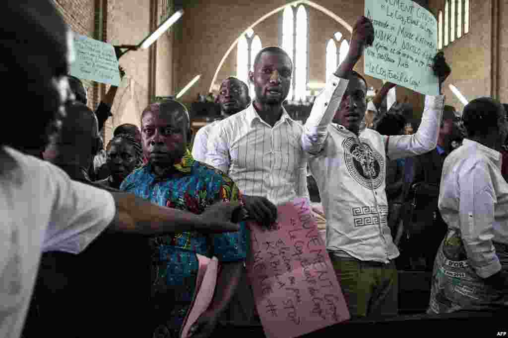 Des manifestants montrent des affiches dans un service catholique pour commémorer les victimes de la répression de la marche du mois dernier, à Kinshasa, le 12 janvier 2018 .