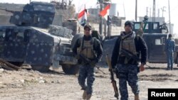 Iraqi security forces carry weapons during a battle with Islamic State militants in the Intisar district of eastern Mosul, Jan. 1, 2017. 