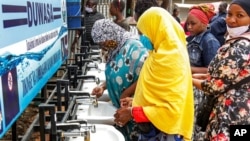 Les gens utilisent une station de lavage des mains installée pour les membres du public entrant sur un marché à Dodoma, en Tanzanie, le 18 mai 2020.