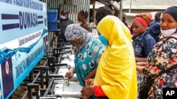 FILE - People use a handwashing station installed for members of the public entering a market in Dodoma, Tanzania, May 18, 2020. Tanzania’s government stopped reporting cases of COVID-19 in May. 