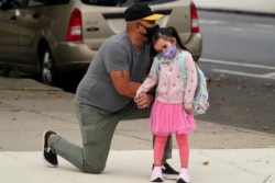 Joel Balcita comforts his daughter Sadie just before she starts her first day of grade 1 at P.S. 130 in the Brooklyn borough of New York City, Sep. 29, 2020.