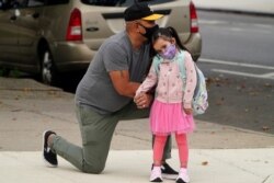 Joel Balcita comforts his daughter Sadie just before she starts her first day of grade 1 at P.S. 130 in the Brooklyn borough of New York City, Sep. 29, 2020.