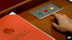 A delegate prepares to press buttons to vote on the draft resolutions during the closing session of the annual National People's Congress held in Beijing's Great Hall of the People on March 16, 2016. 