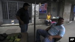 Vendedores ambulantes esperan clientes cerca de un cartel de la campaña de apoyo del presidente de Venezuela, Hugo Chávez, en Caracas, Venezuela.