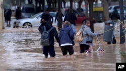 Ljudi se probijaju kroz poplavljene ulice Valensije, 30. oktobar, 2024. (Foto: AP/Alberto Saiz)