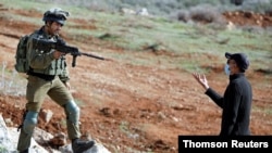 요르단강 서안지구에서 이스라엘 군사가 유대인 정착촌 건설에 반대하는 팔레스타인 시위 참가자에게 총을 겨누고있다.