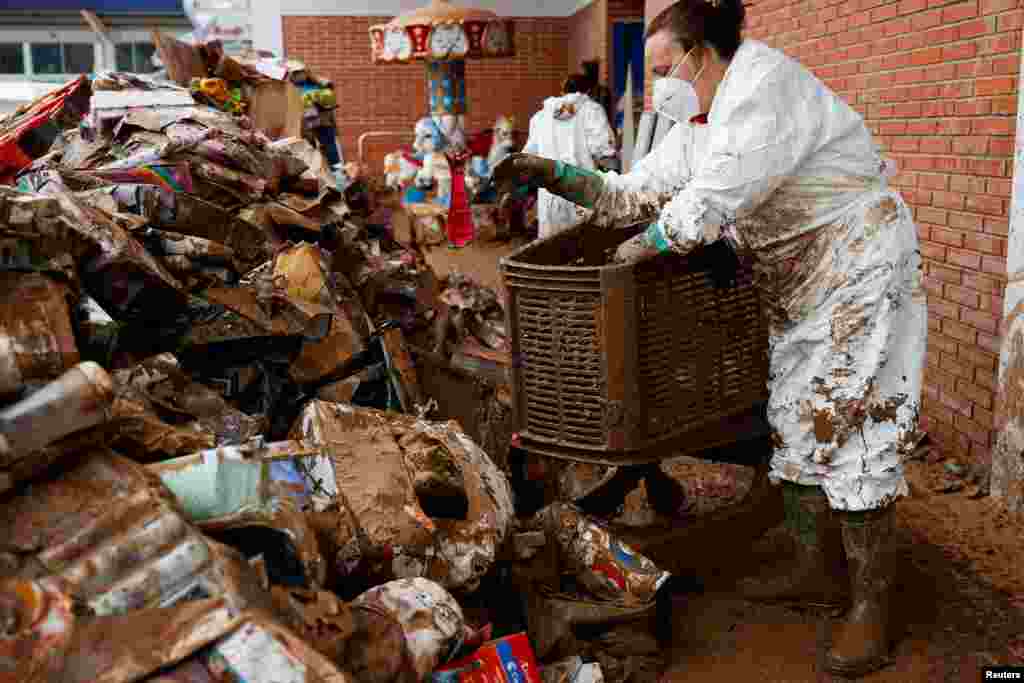 A woman piles up damaged toys outside a toy shop affected by heavy rains at a shopping centre, in Sedavi, Valencia, Spain.