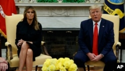 First lady Melania Trump listens as President Donald Trump talks about a plan to ban most flavored e-cigarettes, in the Oval Office of the White House, Sept. 11, 2019, in Washington.