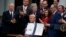 President Donald Trump shows off the "VA Mission Act" during a signing ceremony in the Rose Garden of the White House, June 6, 2018, in Washington. 