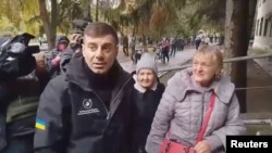 乌克兰议会人权事务专员德米特罗·卢比涅茨在乌克兰赫尔松州奥列什基市迎接前往乌克兰控制区的居民。(2026年10月30日)