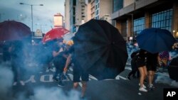 Protesters use umbrellas to shield themselves from tear gas as they face off with riot policemen on a streets in Hong Kong, Sunday, July 28, 2019. Police launched tear gas at protesters in Hong Kong on Sunday for the second night in a row in another…