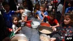 FILE - Displaced Palestinian children line up to receive food in Rafah, on the southern Gaza Strip on April 19, 2024, amid ongoing battles between Israel and Hamas. 