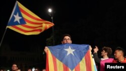 A man holds an Estelada (Catalan separatist flag) as people gather at Plaza Catalunya after voting ended for the banned independence referendum, in Barcelona, Spain October 1, 2017. REUTERS/Susana Vera