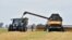 FILE - Grain is moved from a combine harvester into a trailer in the village of Mala Divytysa, Chernihiv region, Ukraine, during a harvest from a few years ago.