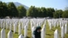A woman leans on a grave stone in Potocari, near Srebrenica, Bosnia, July 11, 2020. Nine newly found and identified men and boys were laid to rest as Bosnians commemorate 25 years since more than 8,000 Bosnian Muslims perished in 10 days of slaughter.
