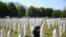 A woman leans on a grave stone in Potocari, near Srebrenica, Bosnia, July 11, 2020. Nine newly found and identified men and boys were laid to rest as Bosnians commemorate 25 years since more than 8,000 Bosnian Muslims perished in 10 days of slaughter.