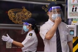 Security guards wearing face shields require people have their body temperature checked at an entrance of a shopping center in Hong Kong, China, Aug. 11, 2020.