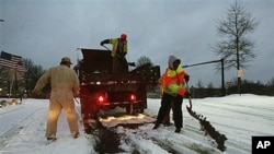 City contractors spread sand and tar on roadways in the early morning hours after an overnight winter storm that so far had deposited seven inches of snow in Johns Creek, Ga., Jan 10, 2011