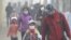 FILE - Young students and their parents wearing masks walk along a street on a hazy day in Harbin, Heilongjiang province, China, Nov. 3, 2015.
