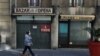 FILE - A person walks a dog past a closed shop during the second national lockdown as part of the measures to fight a second wave of the coronavirus disease in Nice, France, Nov. 17, 2020.