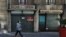 FILE - A person walks a dog past a closed shop during the second national lockdown as part of the measures to fight a second wave of the coronavirus disease in Nice, France, Nov. 17, 2020.