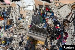 Orang-orang mencari barang sementara ekskavator memindahkan puing-puing dari bangunan yang hancur setelah gempa berkekuatan 7,2 magnitudo di Les Cayes, Haiti, 18 Agustus 2021 (Foto: Reuters)