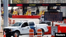 FILE - A U.S. Customs and Border Protection vehicle stands beside a sign reading that the border is closed to nonessential traffic, at the Canada-United States border crossing at the Thousand Islands Bridge, in Lansdowne, Ontario, Sept. 28, 2020. 