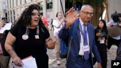 FILE - An activist asks questions on fossil fuels to Senior Advisor to the President for Clean Energy Innovation and Implementation John Podesta at the COP28 U.N. Climate Summit, December 2, 2023, in Dubai, United Arab Emirates.