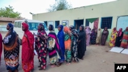 Internally displaced women wait in a queue to collect aid from a group at a camp in Gadaref, Sudan, on May 12, 2024.