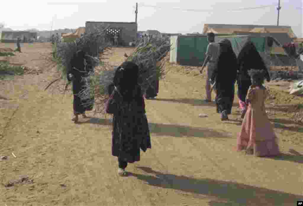Yemeni refugee women carry firewood at the Mazraq Refugee Camp in northern Yemen Friday, Dec. 11, 2009. UNHCR says that the population of the refugee camp has doubled in the last month as civilians continue to flee their homes with fighting between Yemeni