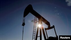 The sun is seen behind a crude oil pump jack in the Permian Basin in Loving County, Texas, U.S., November 22, 2019. REUTERS/Angus Mordant/File Photo