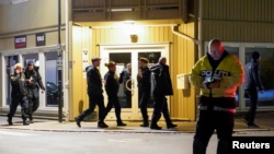Police officers investigate at the scene where an arrow was shot into a wall after several people were killed and others were injured by a man using a bow and arrows to carry out attacks, in Kongsberg, Norway, October 13, 2021.