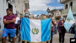 Simpatizantes llevan una bandera de Guatemala mientras escuchan al candidato presidencial Bernardo Arévalo durante un acto de campaña, el domingo 16 de julio de 2023, en Santa María de Jesús, Guatemala.