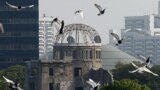Doves fly over Peace Memorial Park with Atomic Bomb Dome in the background, at a ceremony in Hiroshima, August 6, 2015. 