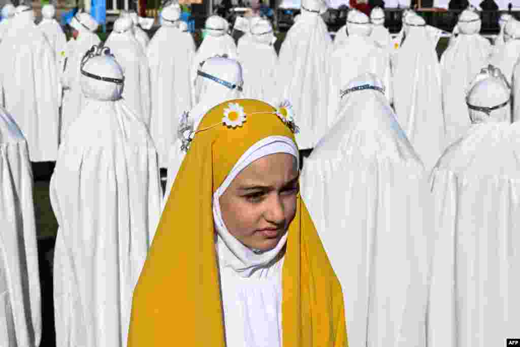 Iraqi Muslim girls, who traditionally begin wearing the hijab, a head covering worn in public at the mandatory age of nine, take part in a ceremony organized at a stadium in Basra. (Photo by Hussein FALEH / AFP)