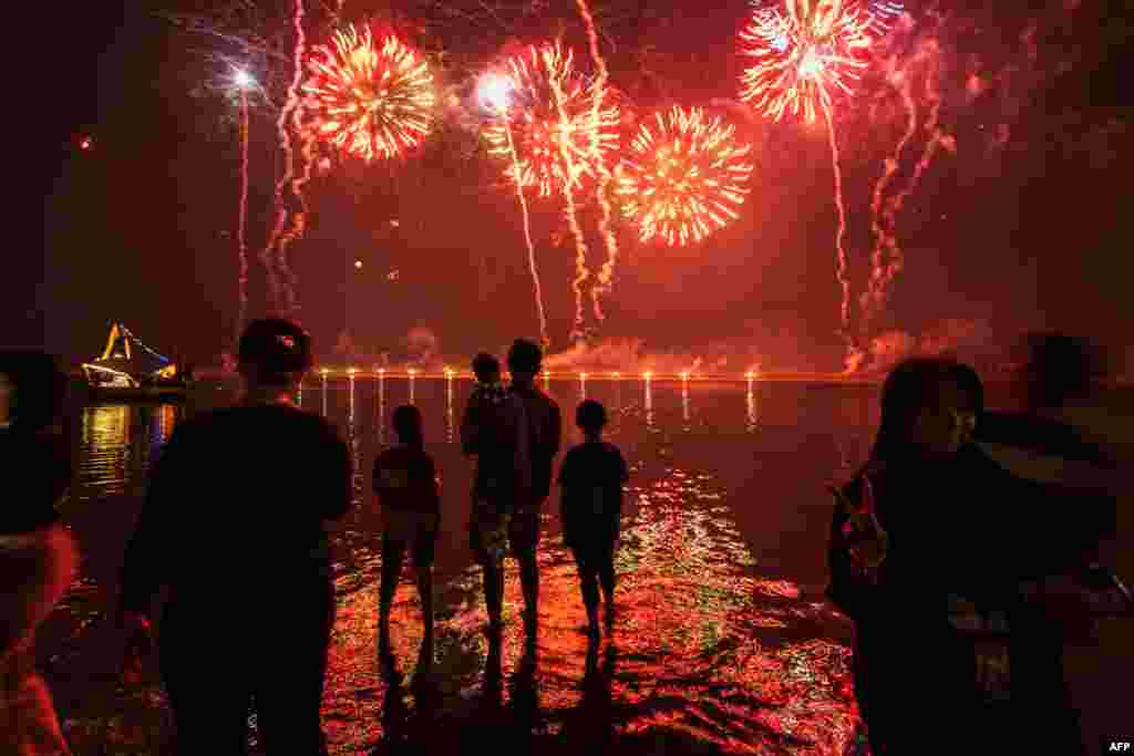 Warga sekitar menyaksikan kembang api saat merayakan Tahun Baru di Pantai Ancol, Jakarta, pada 1 Januari 2025. (AFP)&nbsp;